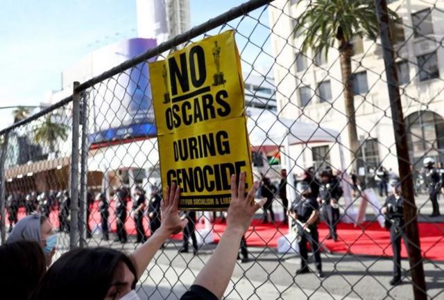 Manifestante segura cartaz em que se lê: 'Não ao Oscar durante o genocídio', durante protesto nas imediações do teatro