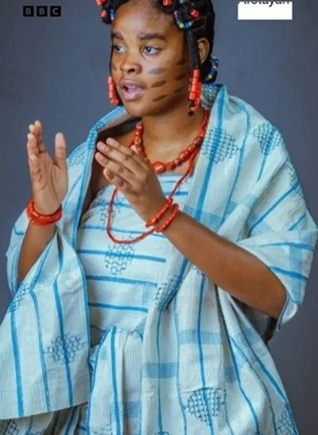 Eyiyemi Afolayan ree to mura fun ere tiata sise, o ro asọ oke sigba aya rẹ, o da irufẹ́ asọ oke naa bora, o lo ilẹkẹ meji si ọwọ ati ọrun rẹ, o si fi ilẹkẹ naa se yẹri eti. O kọ ila ẹrin-mẹrin si ẹẹkẹ rẹ, o si di irun koroba