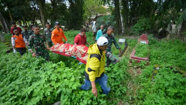 Relawan bencana bersama prajurit TNI dan warga menggotong jenazah korban banjir bandang yang baru ditemukan di Jorong Galuang, Nagari Sungai Pua, Agam, Sumatera Barat, Selasa (14/5/2024). 
