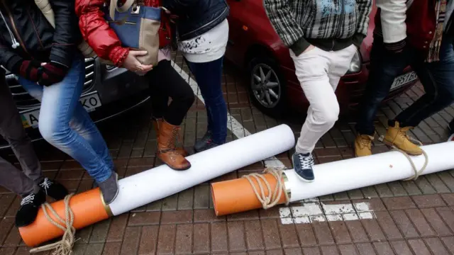 На бруківці лежать муляжі великих сигарет, на них наступили учасники акції протесту. 