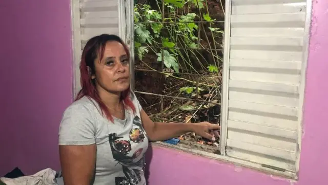 Elisangela com olhar sério em frente a janela