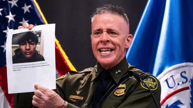 Komandant granične patrole Greg Bovino drži list papira na kojem su prikazani navodni zločini koje je počinio neidentifikovani imigrant 