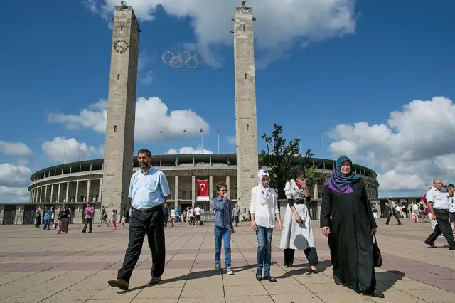 Türkler oy kullanılan bir binanın önünde yürüyor.