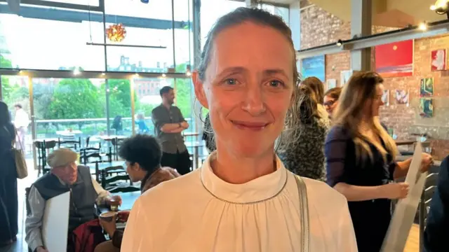 Emily Dalton sonríe a la cámara. Está en la cafetería de un cine.