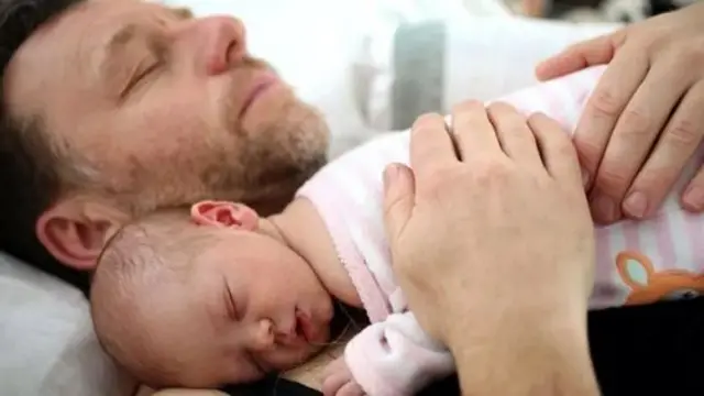 Чоловік спить із дитиною на руках