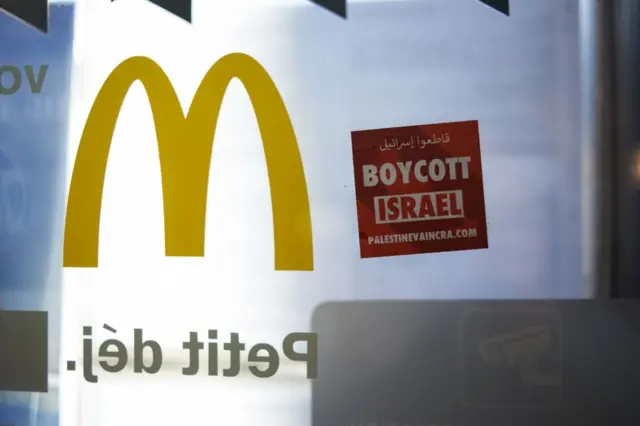 Para pengunjuk rasa menempelkan stiker bertuliskan 'Boikot Israel' di McDonald's ketika ratusan orang berdemonstrasi di Toulouse, Prancis.