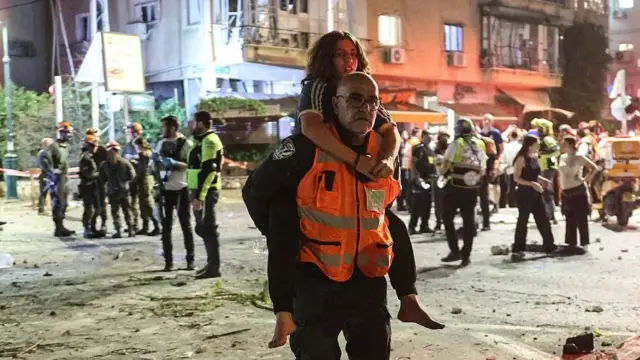 Un rescatista cargando una adolescente tras un ataque iraní