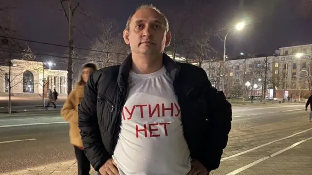 Vitaly Votanovsky vestindo uma camiseta com o slogan 'Não à guerra' escrito em russo