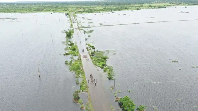 住民が道路を渡るため洪水の中を歩く様子を上空から撮影した写真