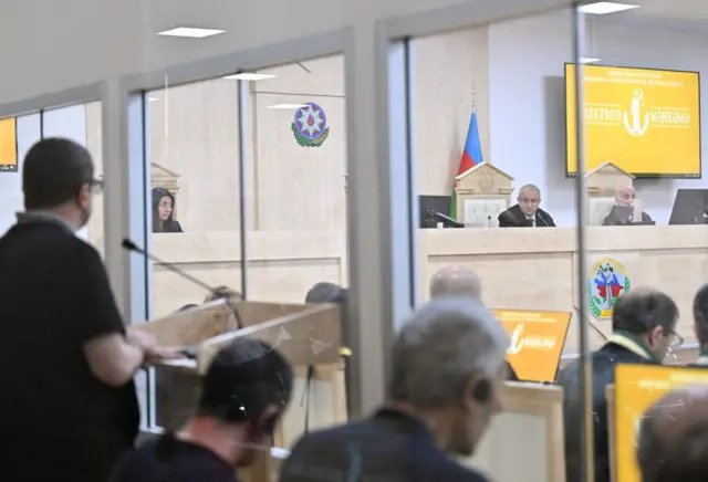 Обвиняемые в зале суда, в застекленной кабине.