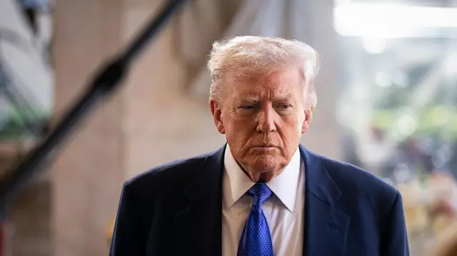 Donald Trump, con traje oscuro, corbata azul y gesto pensativo. 