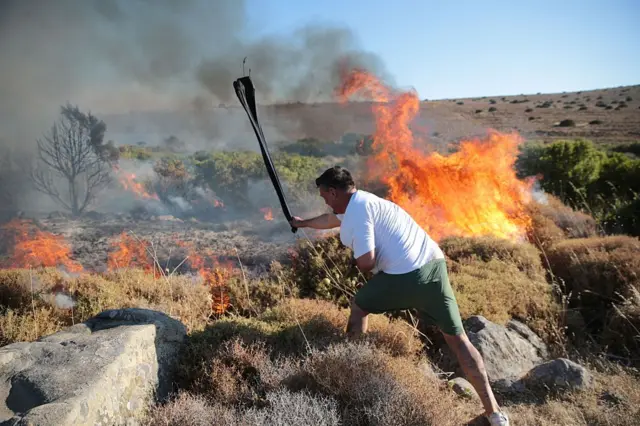 3 Temmuz'da Çeşme'de yangın söndürme çalışmalarına katılan bir gönüllü. Bu kişi, elindeki dalla makilerdeki yangını söndürmeye çalışıyor. 