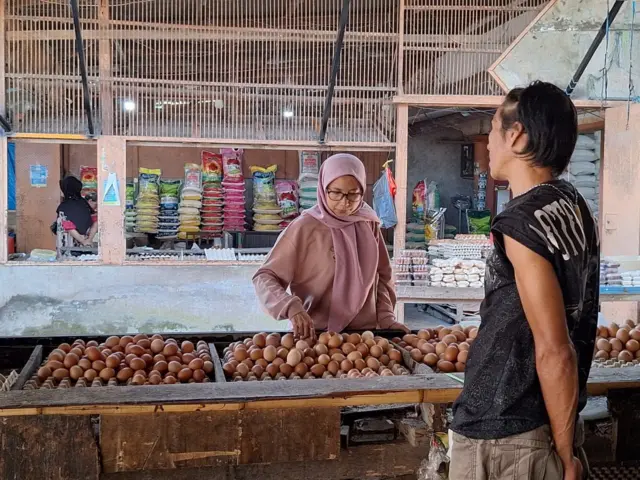 Pedagang saat melayani salah satu pembeli telur di tokonya.