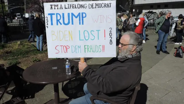 Человек сидит с плакатом