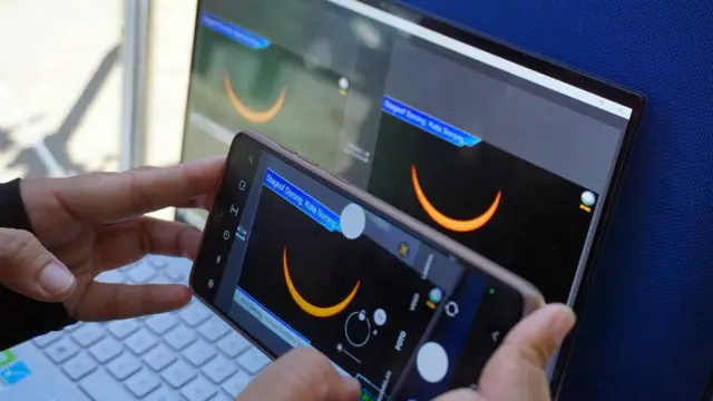 Warga melihat fenomena gerhana matahari dari layar di kantor BMKG Kota Sorong, Papua Barat Daya, Kamis (20/4). 