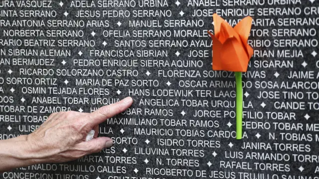 Una mano señala un nombre de una lista en el Monumento a la Memoria y la Verdad en San Salvador, El Salvador