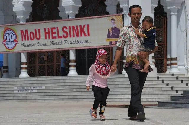 Seorang pria Aceh dan dua anak meninggalkan lokasi setelah upacara peringatan 10 tahun perjanjian damai Helsinki antara kelompok pemberontak Gerakan Aceh Merdeka (GAM) dan pemerintah Indonesia di Masjid Baiturrahman, Banda Aceh, Provinsi Aceh, pada 15 Agustus 2015.