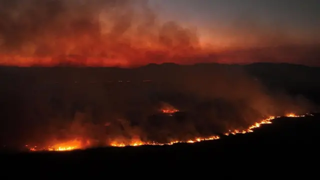 Imagem feitaqual o erro da bet365drone mostra uma grande área pegando fogo durante a noite.