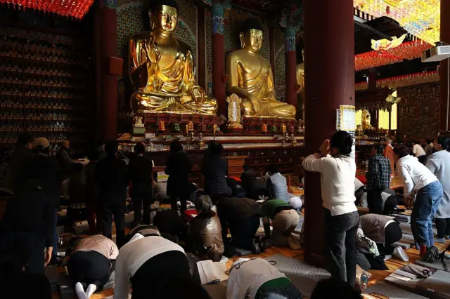 서울 조계사 불상 앞에서 수험생 부모 및 가족들이 수능 기도를 드리고 있다