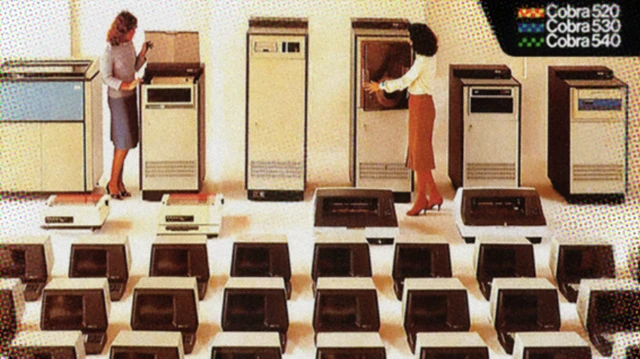 Imagem publicitária mostra uma linha de computadores de grande porte da série Cobra 520, 530 e 540, com duas mulheres ao lado das máquinas. À frente, aparecem diversas unidades menores de terminais ou periféricos dispostas em fileiras.