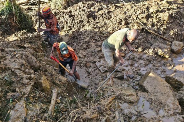 Hombres con palas buscan cuerpos o posibles sobrevivientes del deslizamiento de tierra en Papúa Nueva Guinea.