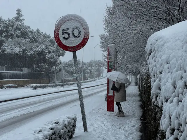 Женщина держит зонт, ожидая автобуса, во время шторма «Кристин», обрушившегося на несколько районов Испании и Португалии. Фотография сделана в Галапагаре, на окраине Мадрида 