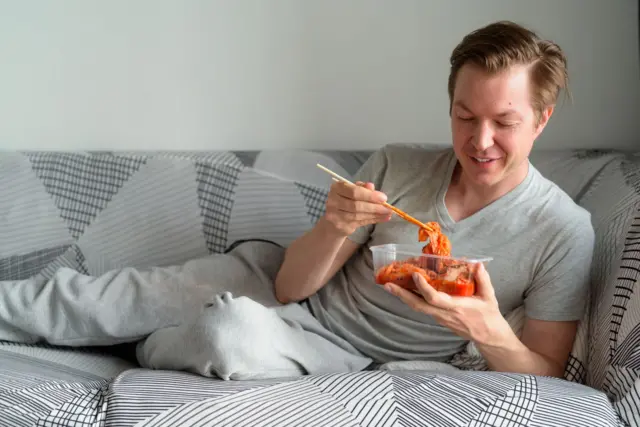 Homem comendo kimchi na cama