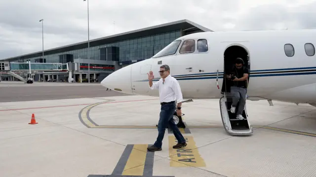 El expresidente Juan Orlando Hernández baja del vuelo privado en el que llegó a Honduras tras su indulto.
