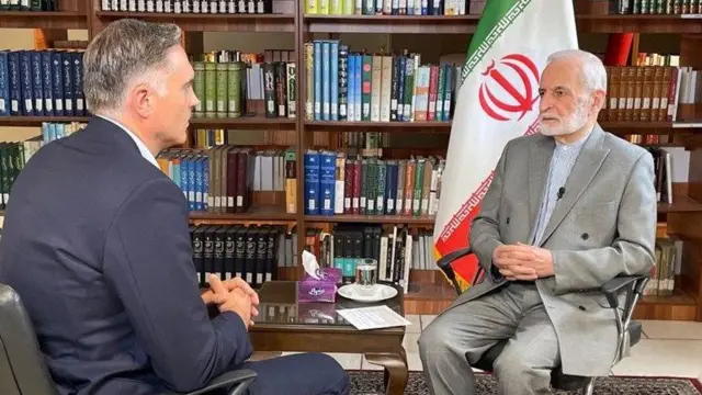 کمال خرازی در مصاحبه با خبرنگار سیانان در تهران-پشت سر آقای خرازی کتابخانه و پرچم ایران دیده میشود.