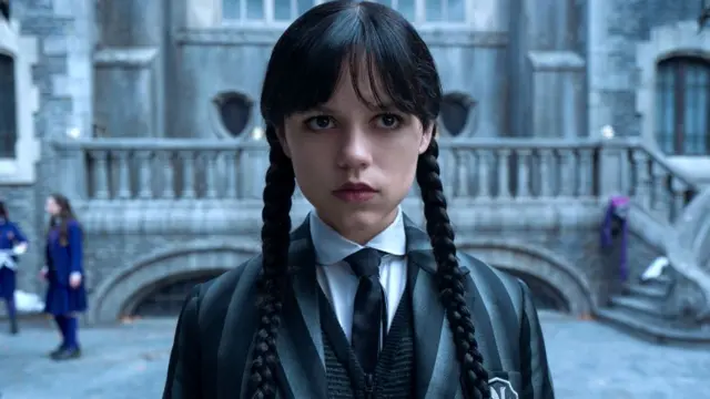 Jenna Ortega em uma das cenas da série. Ela usa uniforme do colégio e usa tranças