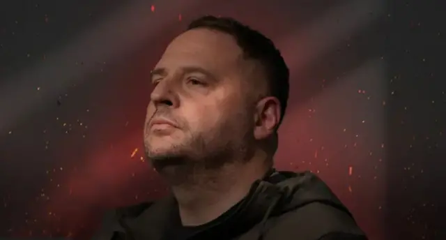 Єрмак в оливкому дивиться у бік на червоному фоні з іскрами навколо 