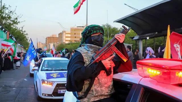Una persona sostiene un rifle mientras viaja en un automóvil durante una manifestación progubernamental por el Día del Ejército Nacional el 17 de abril de 2026 en Teherán, Irán.