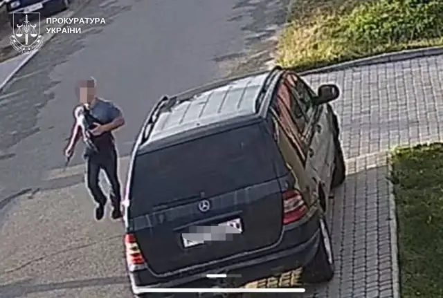 Чоловік із заблюреним обличчям наближається до чорного авто "Мерседес"