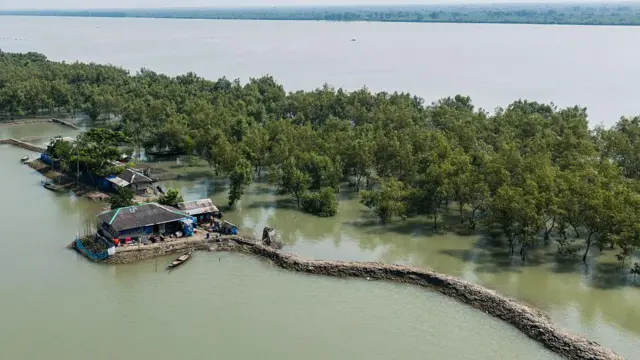 Esta fotografía aérea, tomada el 20 de octubre de 2025, muestra una vista general de las casas en un terraplén del río Kholpetua, junto a un manglar en Sora, una aldea vulnerable a la subida del nivel del mar en el distrito de Khulna, en la costa de Bangladesh.