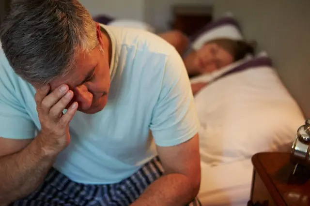 Man Awake In Bed Suffering With Insomnia Late At Night