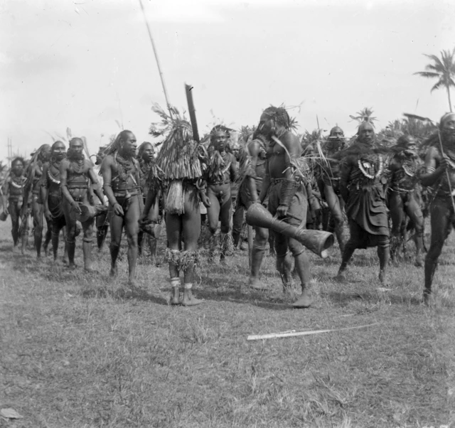 Foto lawas orang-orang Papua sedang membawa alat musik tifa.