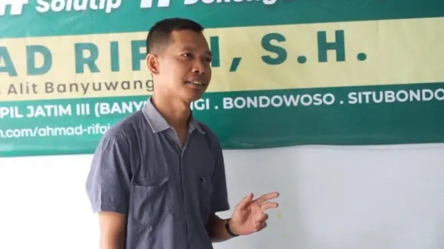 Ahmad Rifai in front of campaign banner