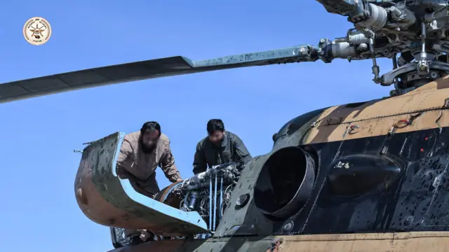 دو نفر در بالای هلیکوپتر در حال نگاه به موتور هلیکوپتر ام ۱۷