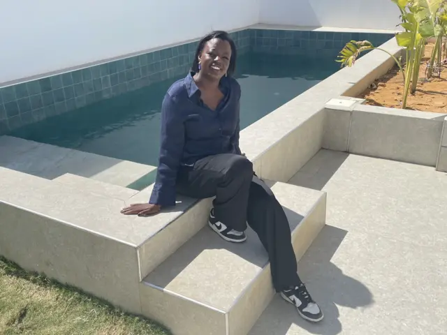 Coumba Sow au bord de la piscine d'une maison témoin
