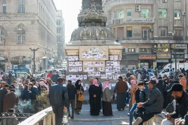 خلک د خپلو نژدې کسانو او ورکو شوو کسانو په لټه کې دي، د بشار اسد ضد اعتراضونو د یاد لپاره په دېوال کې په مرجه چوک کې پوسر
ټرونه لګولي دي