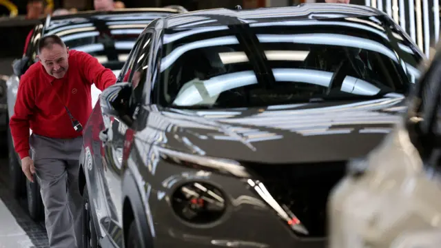 Un trabajador con un jersey rojo examina un modelo de automóvil Nissan Juke terminado cuando sale de la línea de producción en la fábrica de automóviles Nissan en Sunderland.