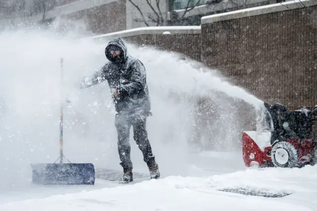 Мушкарац чисти снег испред зграде 