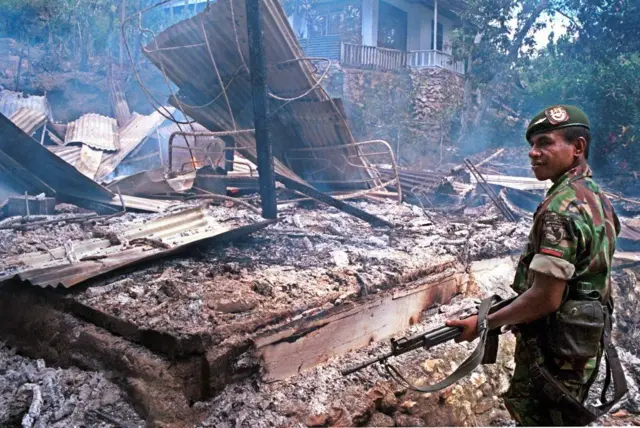 Seorang tentara berjaga di dekat rumah yang terbakar setelah serangan bom molotov di Desa Ahuru, di pinggiran timur Ambon, 27 Februari 1999.