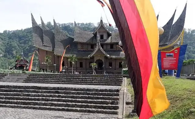 Bendera Minangkabau dengan latar belakang Istano Pagaruyuang.