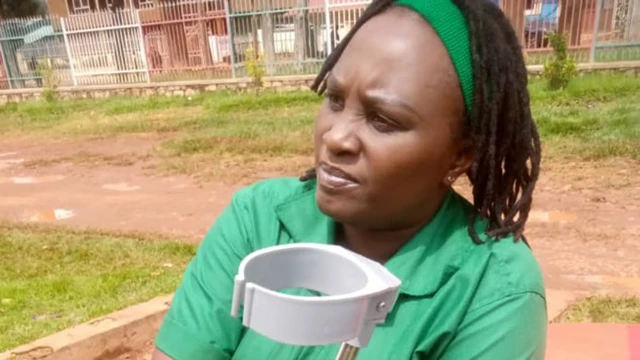 Ifoto y'umumenyeshamakuru w'Umurundi Sandra Muhoza afise imbago, yambaye ishati y'urwatsi rubisi iranga abanyororo mu Burundi, inyuma yiwe hirya hari uruzitiro rw'ivyuma. 