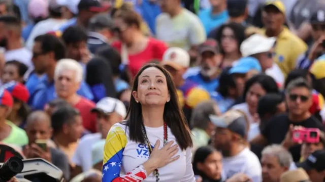 ماریا کورینا ماچادو در میان جمعیت دست راستش را روی سینه گذاشته به بالا نگاه می‌کند