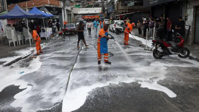 Funcionários da Prefeitura lavam uma rua na favela da Penha no Rio de Janeiro.
