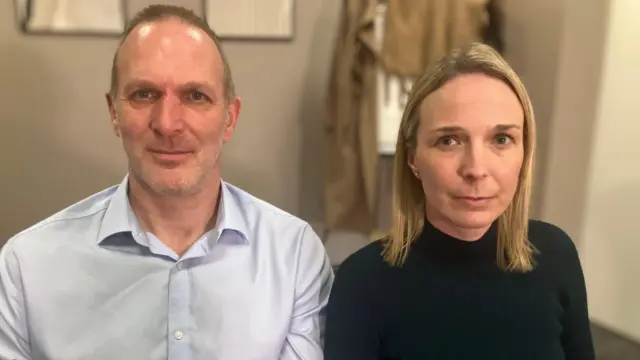 Джек і Сара Гокінс дивляться в камеру під час інтерв'ю BBC. Джек одягнений у світло-блакитну сорочку. Сара має пряме світле волосся та чорний топ.