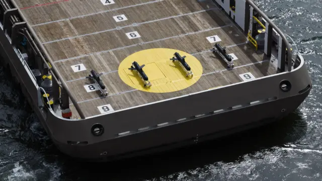 甲板上に一列に並んだグライダー4機を搭載した艦船の空撮映像