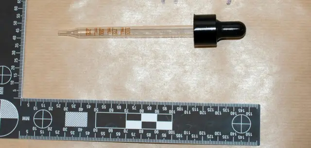 Pipet bening untuk mengeluarkan cairan obat bius. Penggaris hitam dan putih ditampilkan untuk menggambarkan skala.